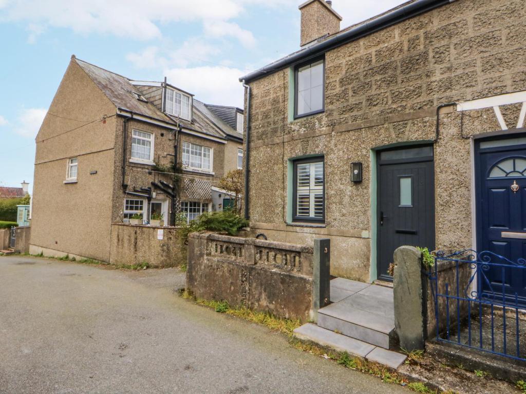 an old brick house with a blue door at East meets West in Criccieth