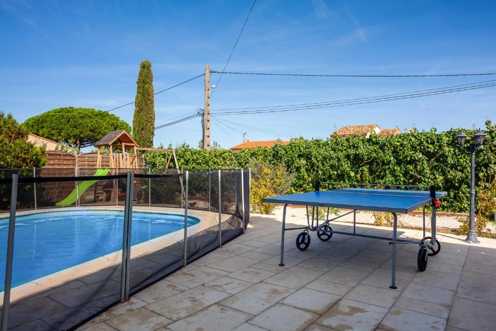 a ping pong table on a patio next to a pool at Maison Roxane in Six-Fours-les-Plages