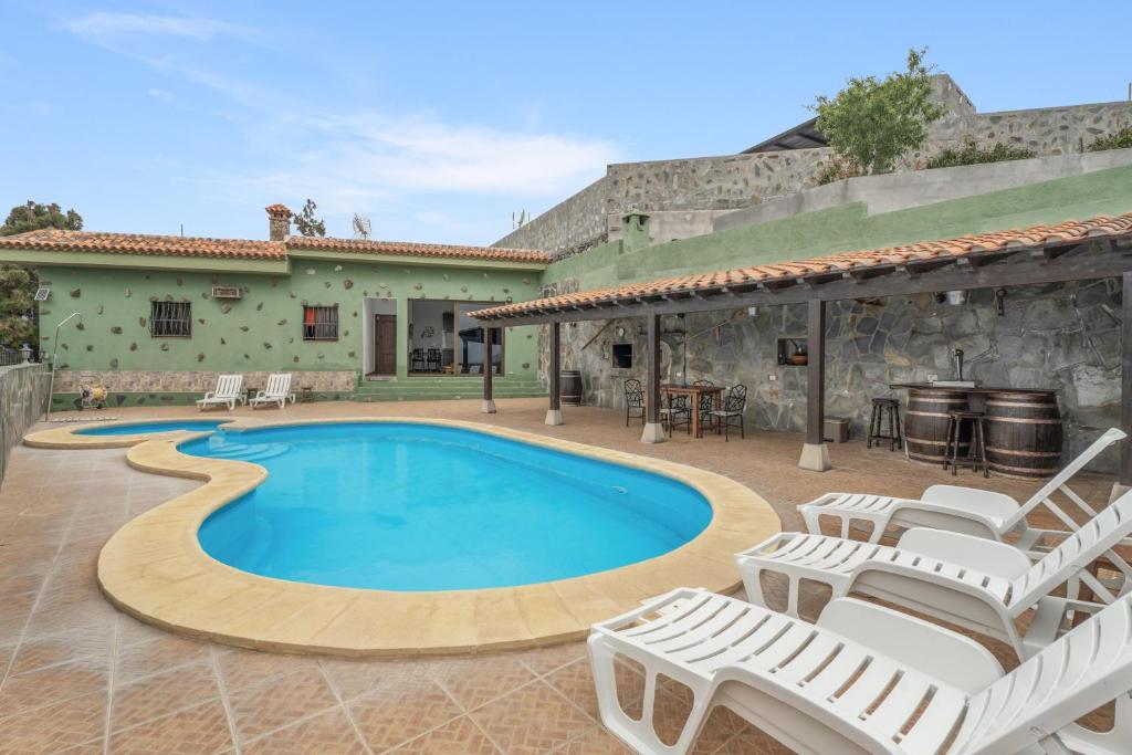 a swimming pool with chairs and a house at Casa Rural Tijoco in Adeje