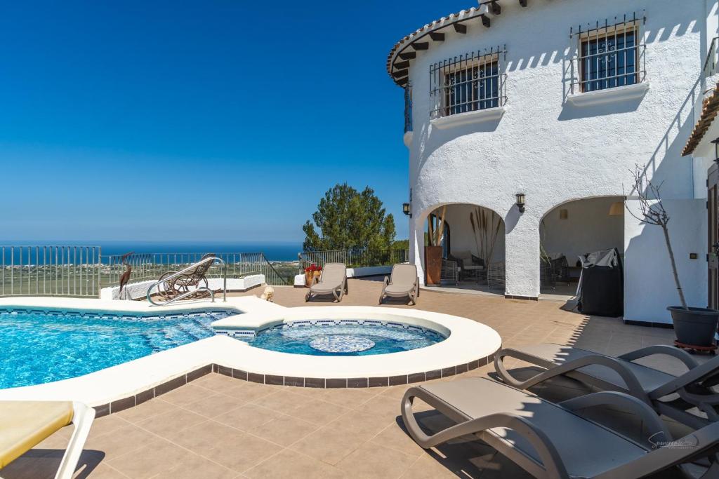 a patio with a pool and chairs next to a building at Villa Amalia in Denia