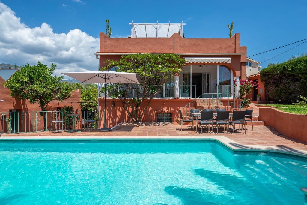 a villa with a swimming pool in front of a house at Villa Tessa in Marbella