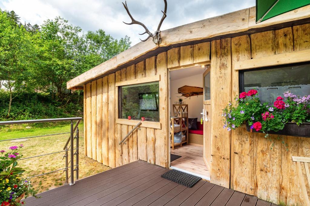 a wooden building with a door and flowers on it at Haus am Bach in Schönmünzach