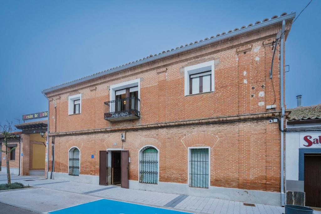 a red brick building with a balcony on a street at Casa Tilde in Matapozuelos