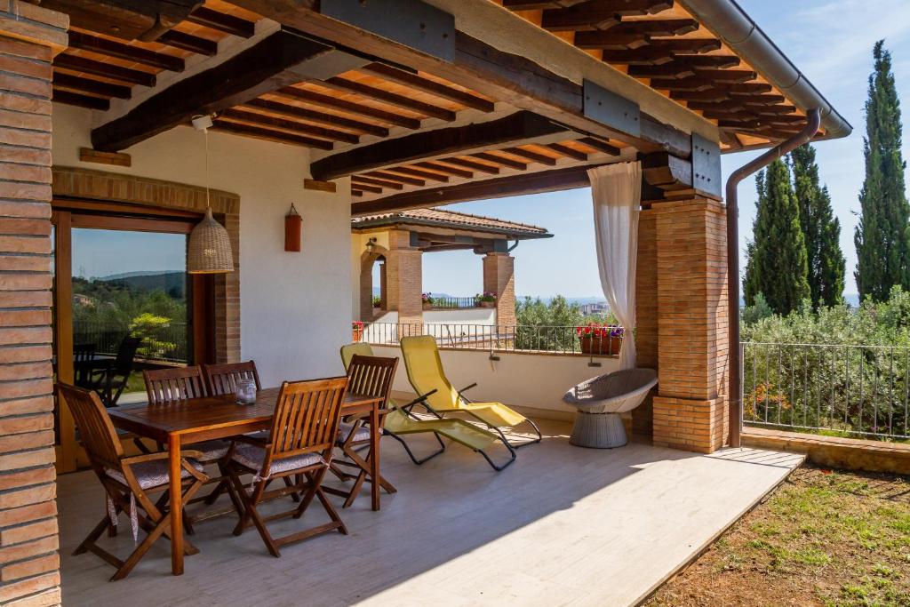 a patio with a wooden table and chairs on it at Villa Glicine - Colleberto in Follonica