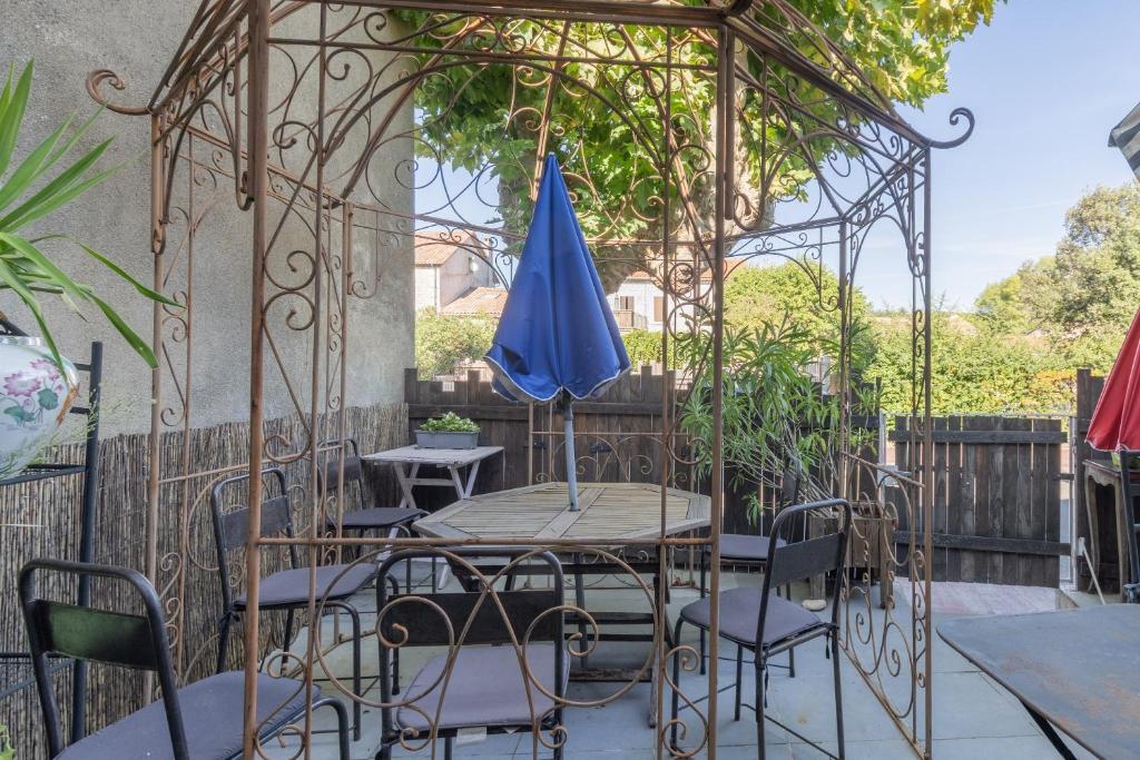 a table and chairs under a gazebo with a blue umbrella at Appartement de charme in Ruoms