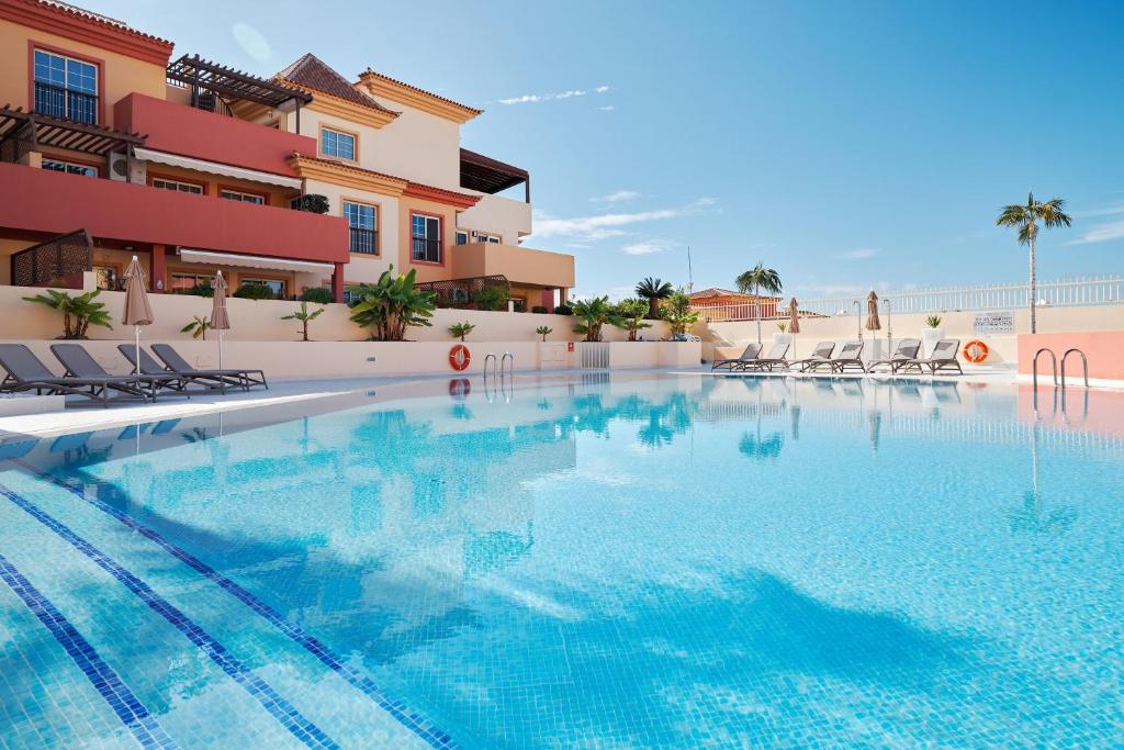 a swimming pool in front of a building at Terrazas del Duque Beach Apartment in Adeje