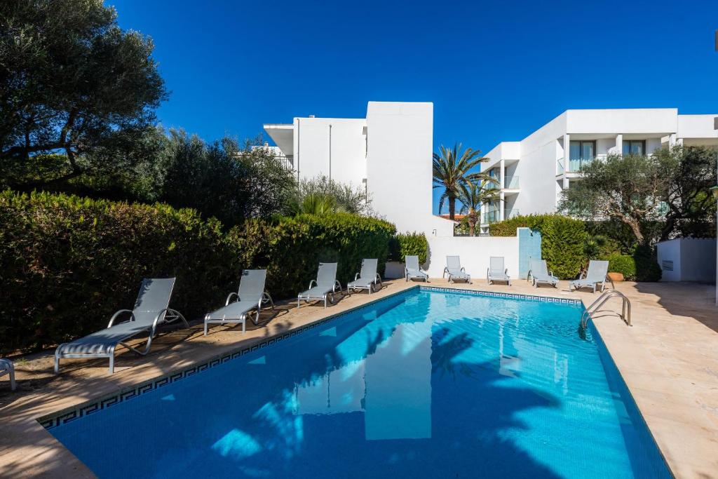 a swimming pool with chairs and a building at Apartamento Bon Aire N4 in Cala Ferrera