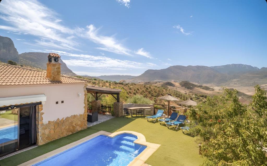 a villa with a swimming pool and mountains in the background at La Cañada in El Gastor
