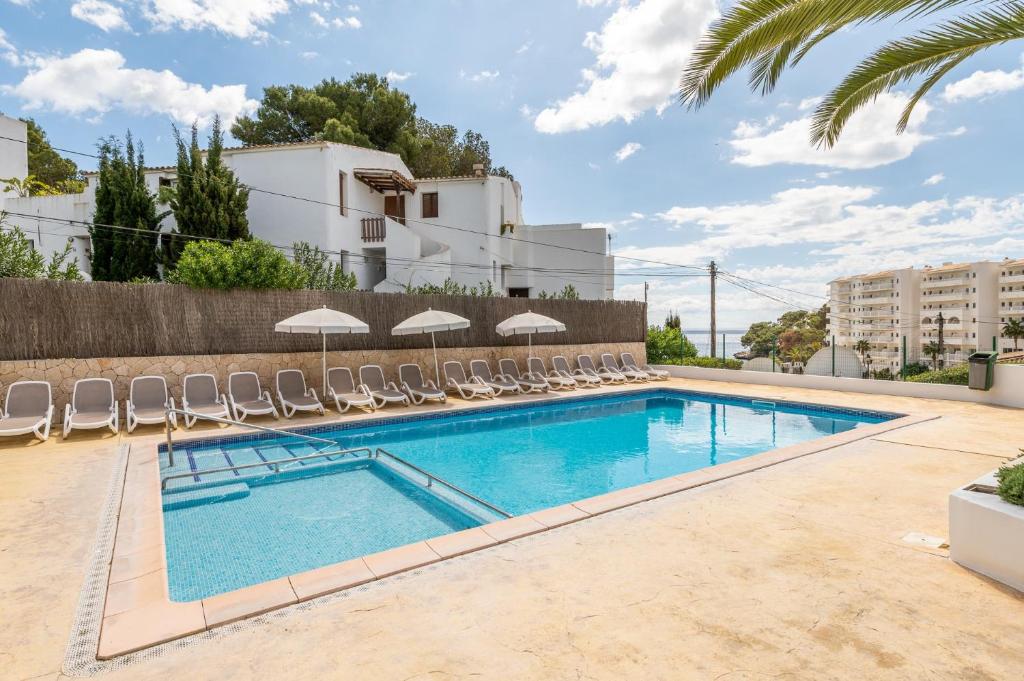 a swimming pool with chairs and umbrellas at Apartamento Poseidonia in Felanitx