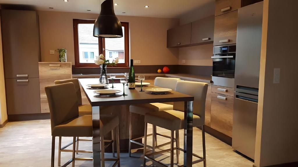 a kitchen with a wooden table and chairs in a kitchen at Gîte La Maison De Caroline, Spa in Sigolsheim