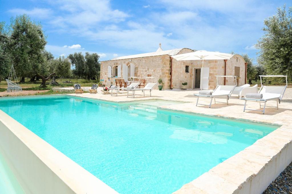 a swimming pool in front of a house at Trullo Delori with infinity Pool in Villa Castelli