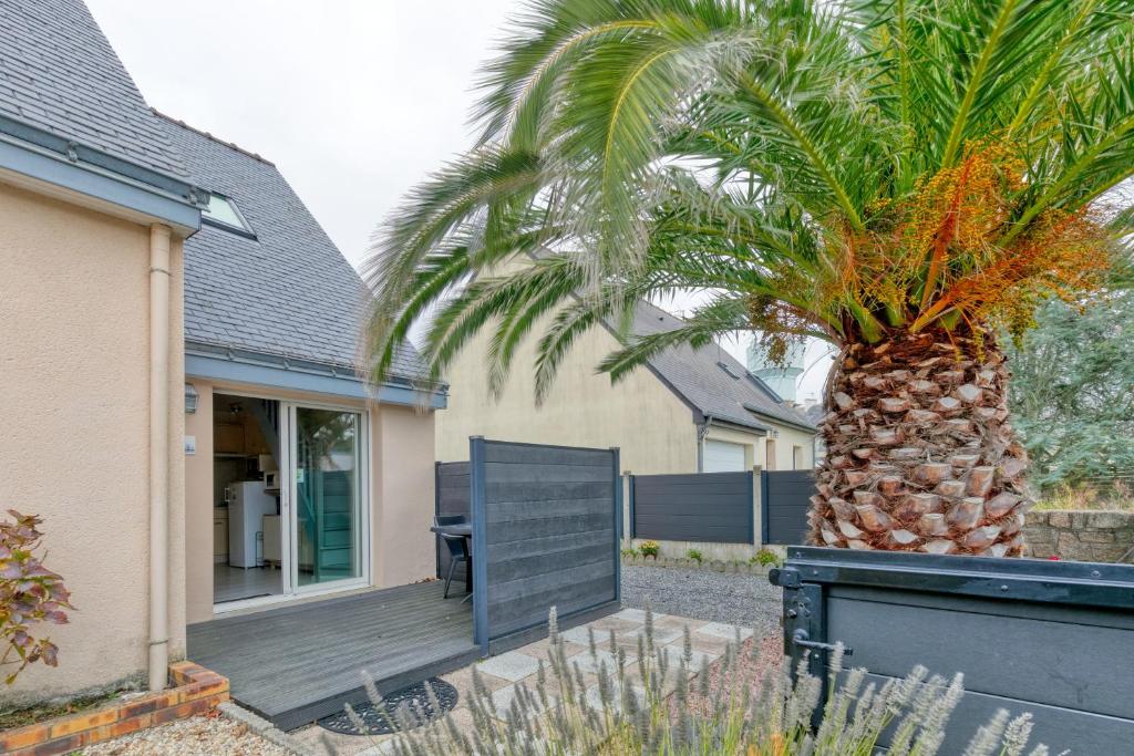 a palm tree in front of a house with a sign at Le pré Nantais proche plage in Le Croisic