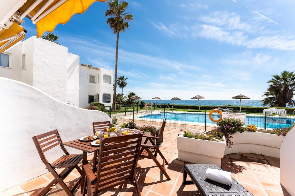 a patio with a table and chairs next to a pool at Seafront Beach house Rocas del Mar in Mijas