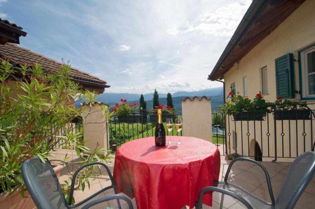 a red table with chairs and a wine bottle on it at Weingut Lieselehof Apt Vitis in Caldaro