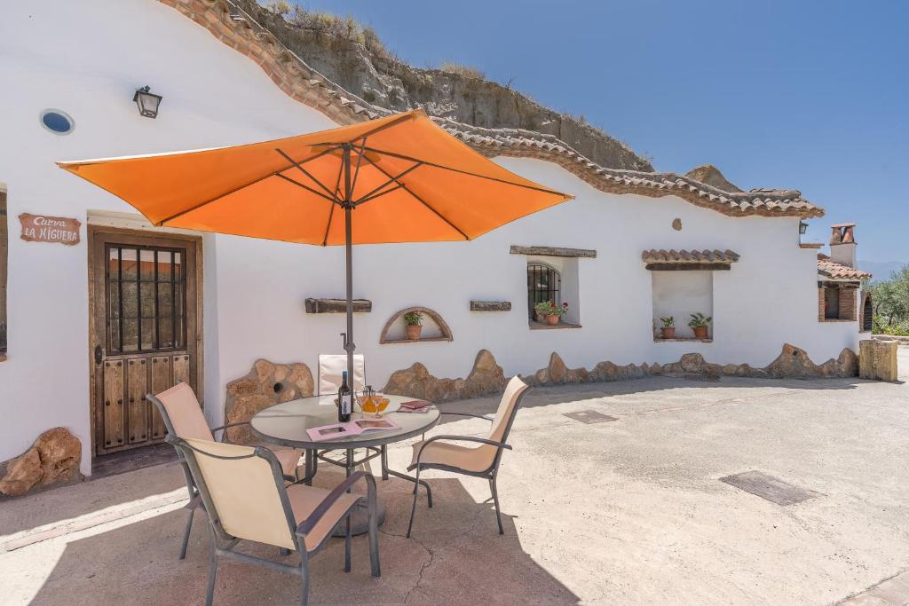 a table and chairs with an umbrella on a patio at La Higuera in Benalúa de Guadix