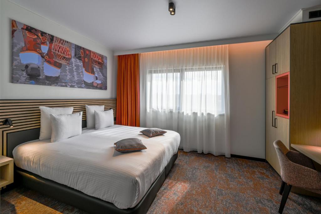 ein Schlafzimmer mit einem großen Bett und einem Schreibtisch in der Unterkunft Orange Hotel La Louvière in La Louvière