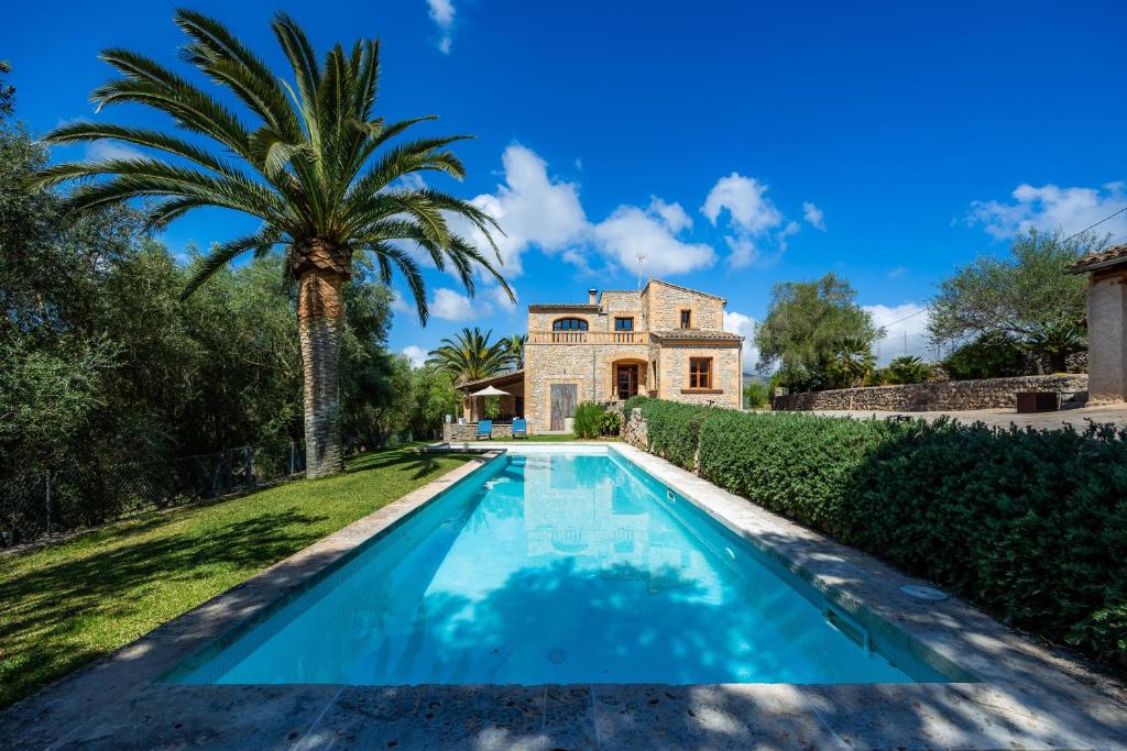 a swimming pool in front of a house with a palm tree at Son Calletes in Artá