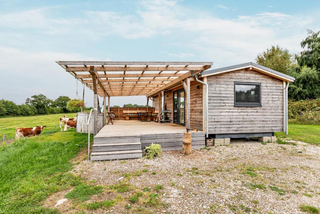 a small cabin with a wooden deck in a field at Naturpur Tinyhouse in Osterrade