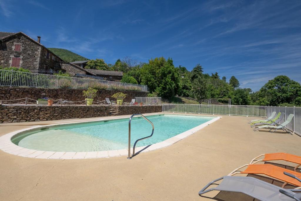 a swimming pool with two chairs and a fence at Maison Chloé - Mas Lachamp in Gravières