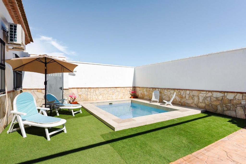 a swimming pool with two chairs and an umbrella at Casa Miró in Humilladero