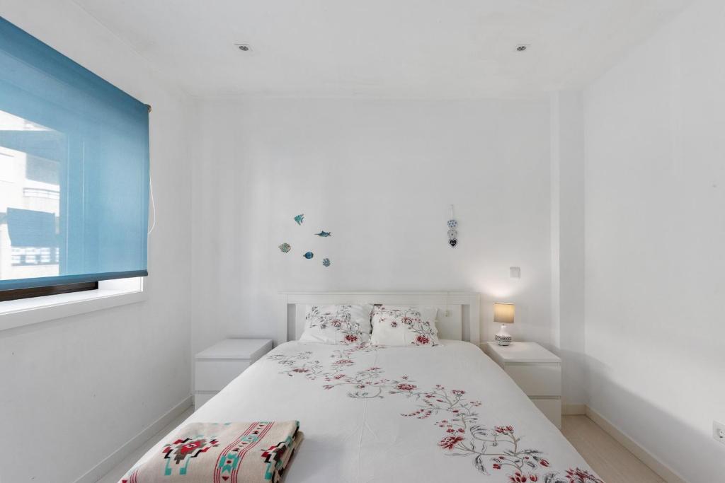 a white bedroom with a bed and a window at T2 Furadouro 30m from the beach in Ovar