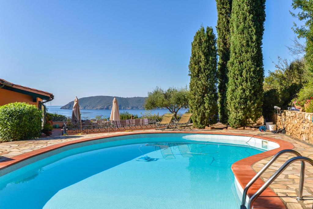 a swimming pool with trees and a view of the water at Elba Offsite Villa in Capoliveri