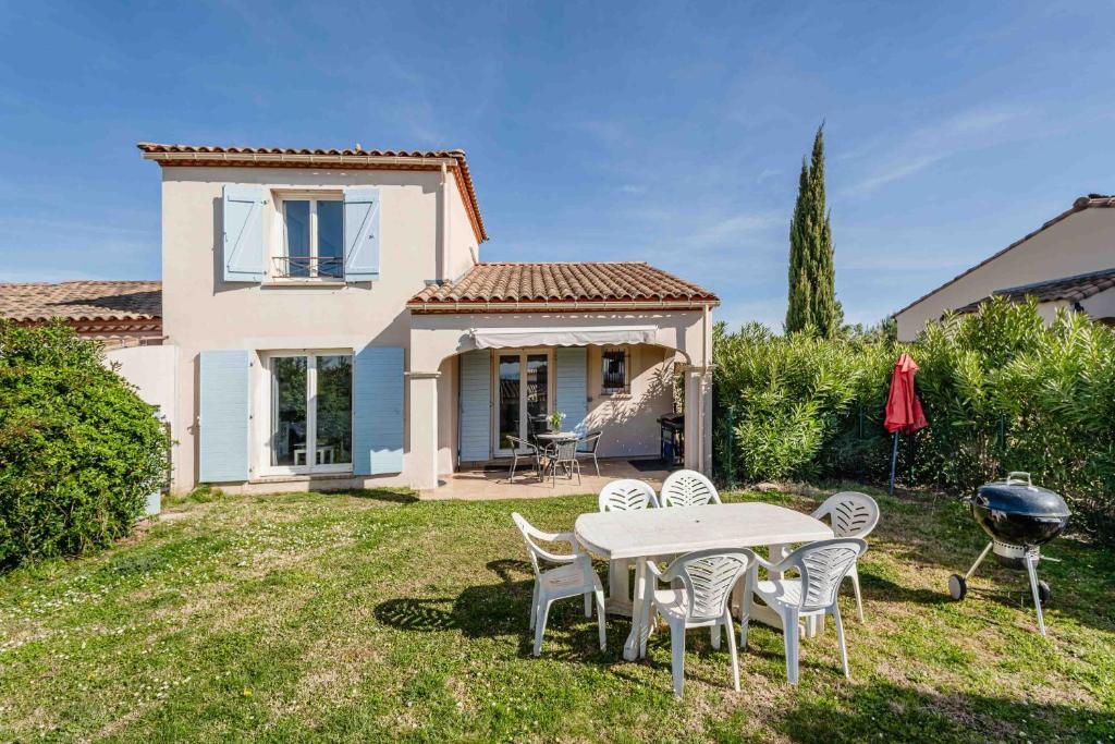 a backyard with a table and chairs and a grill at Résidence du lac de Jouarres in Homps