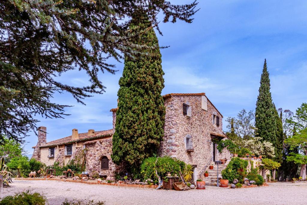a large stone house with a large tree at Masia Mimosa Completa in Darnius