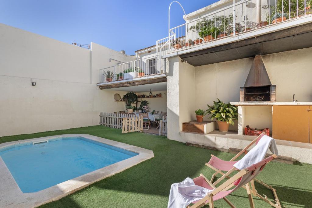 a house with a swimming pool and two lawn chairs at Cal Cabrer in Sant Jaume dels Domenys