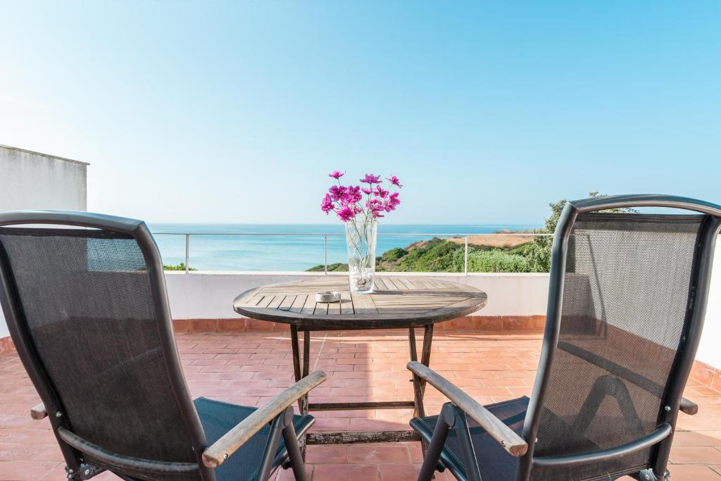 a table and two chairs with a vase of flowers at Casa Fuente del Sol in Conil de la Frontera