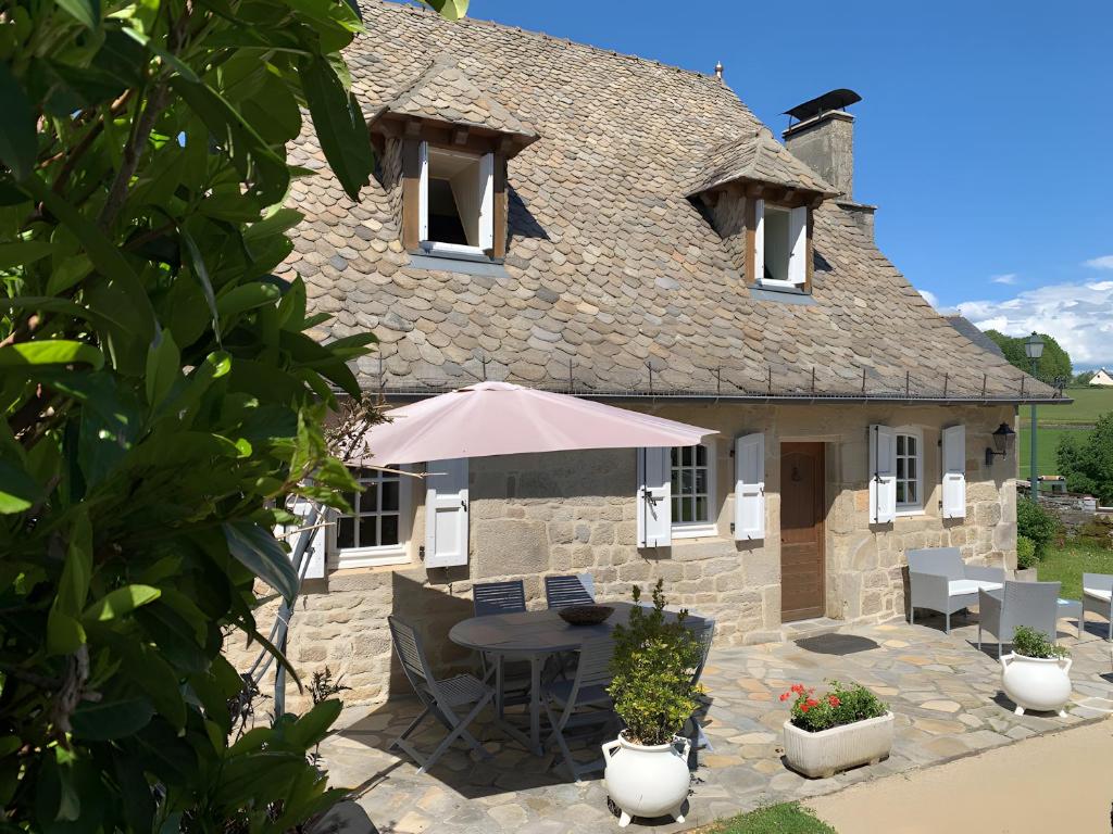 a stone house with a table and an umbrella at Gite rural La Madeleine in Saint-Mathurin-Léobazel