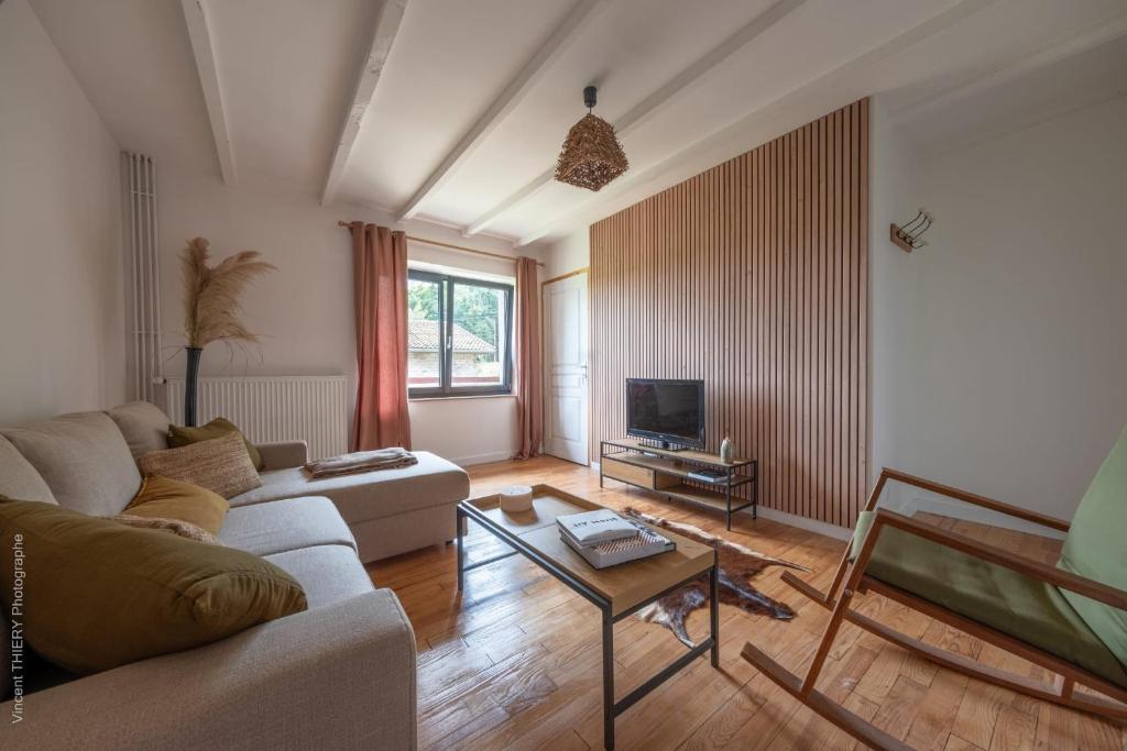 a living room with a couch and a tv at Charming Gîte Le 1681 Xl in Girancourt