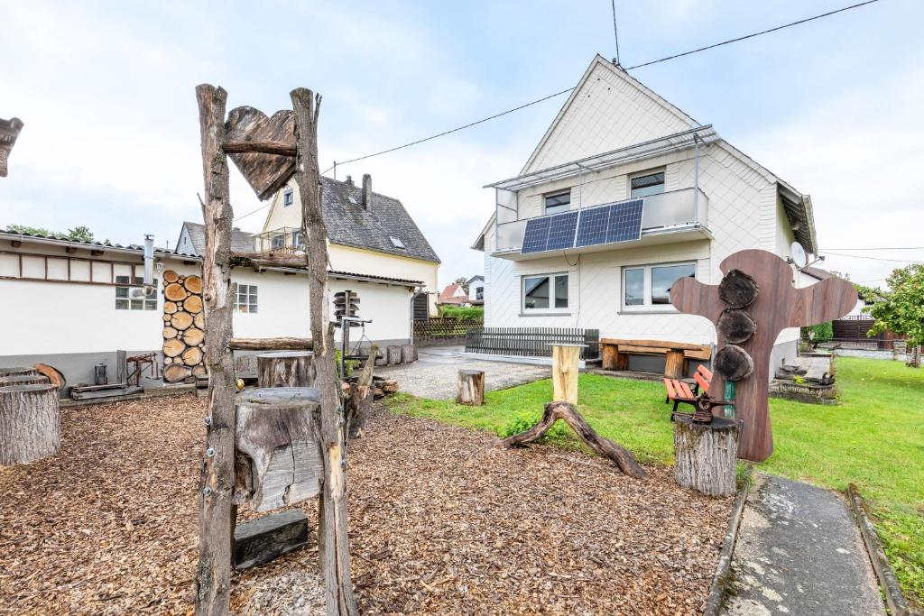 a garden with wooden sculptures in front of a house at Ferienhaus Soonwald Liebe in Seesbach
