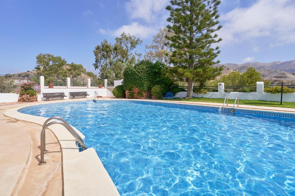 a large swimming pool with blue water in a yard at Atalaya in Almuñécar