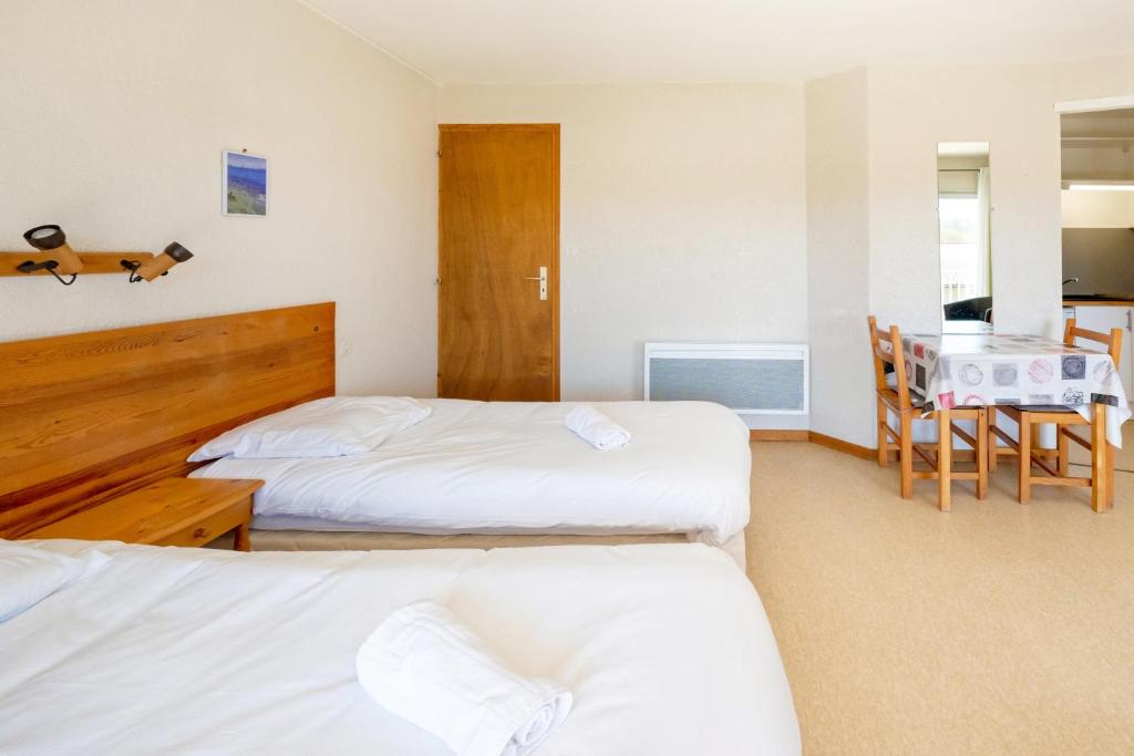 a hotel room with two beds and a table and a dining room at Les Mimosas - Appartement 12 in Cazaubon
