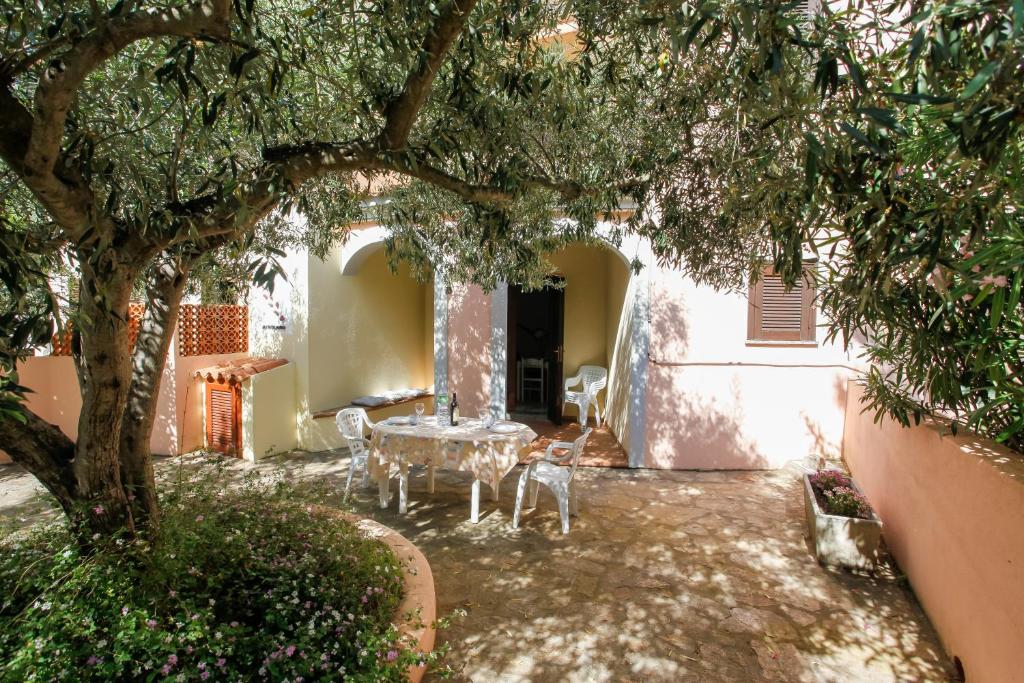 a patio with a table and chairs under a tree at mirtagru appartamento dell'oleandro in Budoni