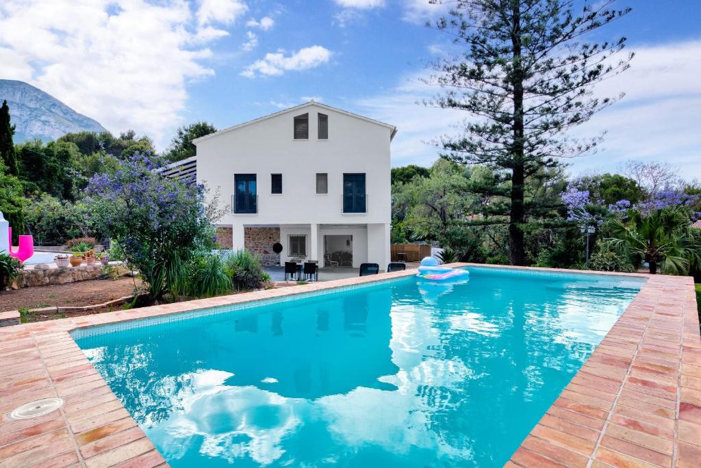 a villa with a swimming pool in front of a house at Araucaria in Denia