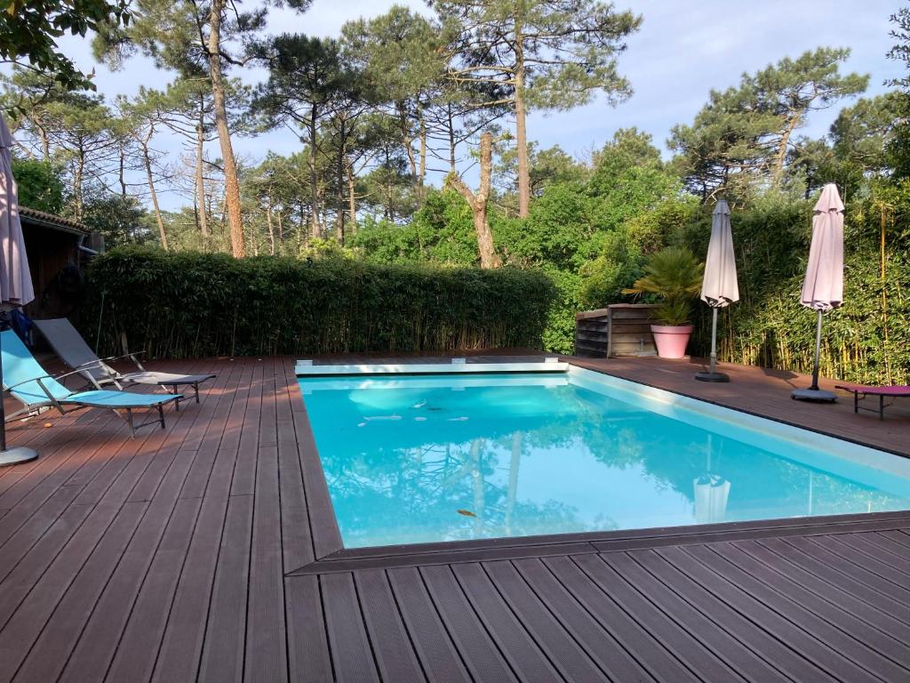 a swimming pool on a wooden deck with a patio at Chambre d'hotes La Rambleur in La Teste-de-Buch