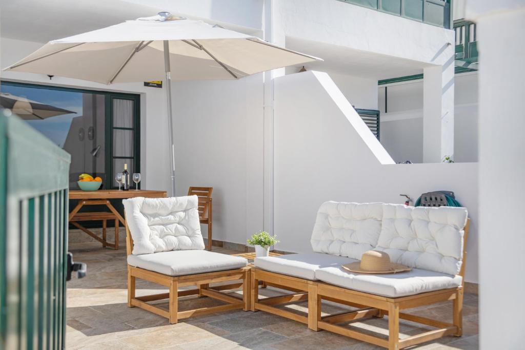 a patio with two chairs and an umbrella at Sin Prisa, con Brisa in Costa Teguise