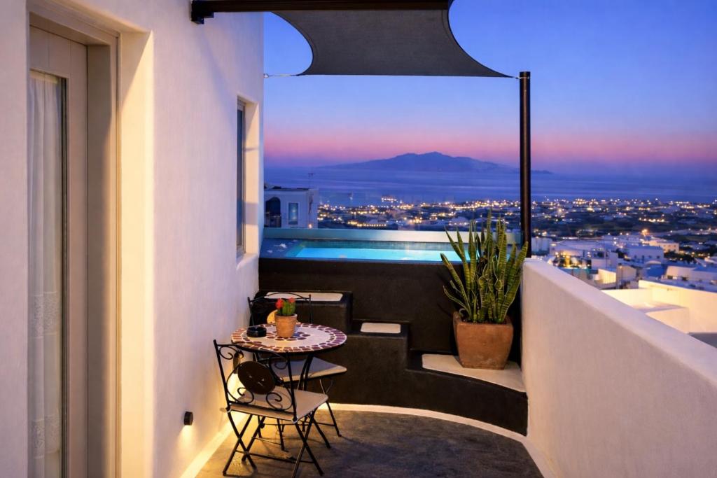 a balcony with a table and a view of the city at Tiara Suites Fira - Cycladic & Cave in Fira