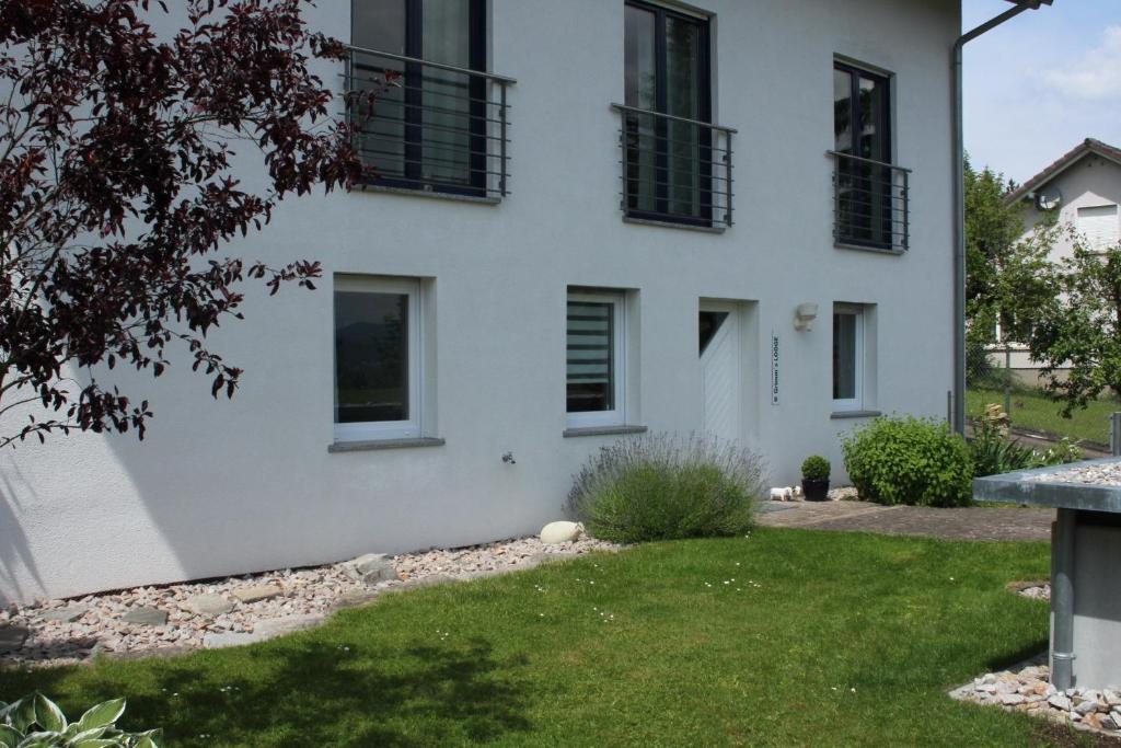 a white house with black windows and a yard at Grimm's Lodge in Lörrach
