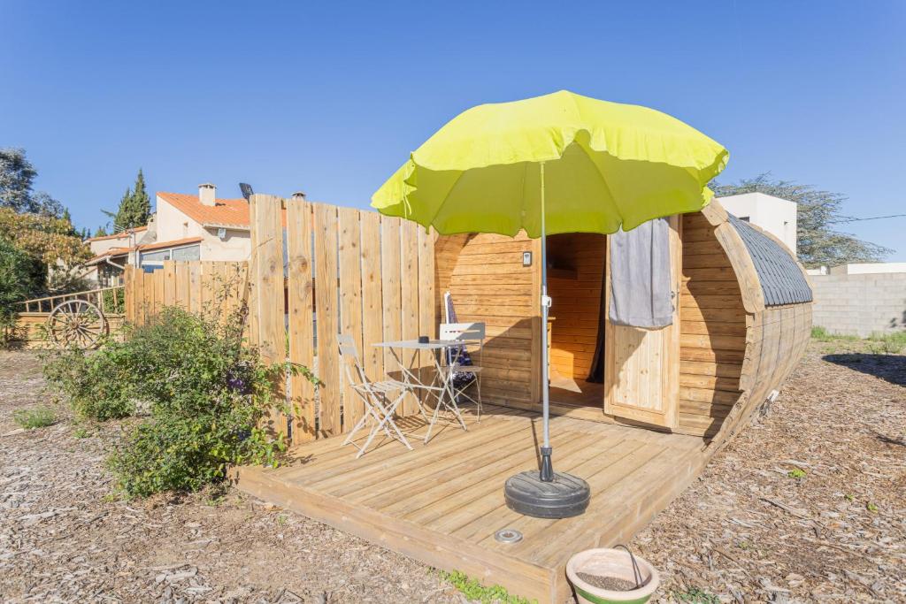 ein kleines Holzhaus mit einem grünen Regenschirm in der Unterkunft Barrel Violet in Saint-André