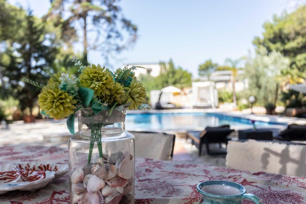 a vase with flowers in it on a table near a pool at Villa Sole With Pool and Sauna in Lecce