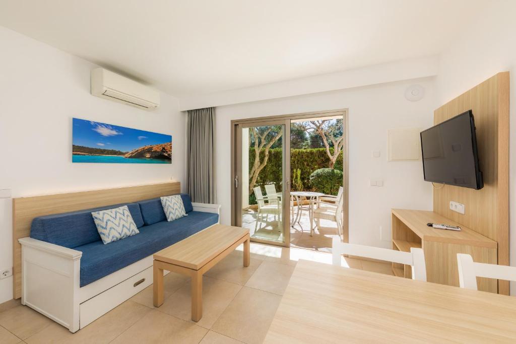 a living room with a blue couch and a tv at Apartamento Bon Aire N1 in Cala Ferrera