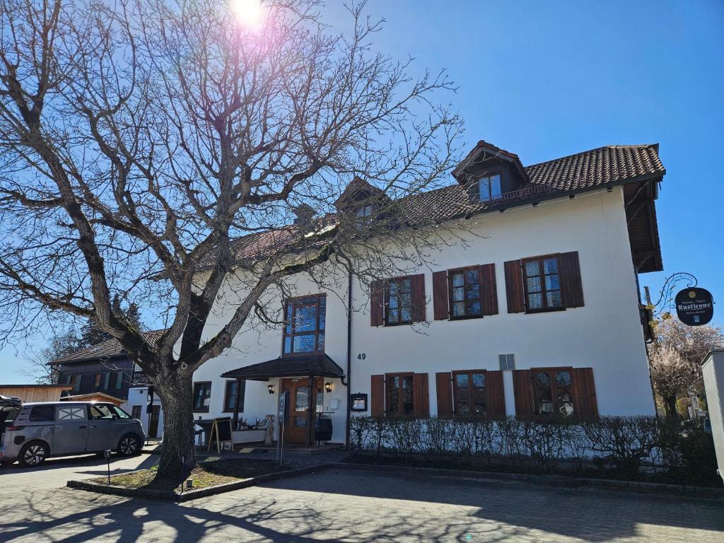 a white house with a tree in front of it at Hotel Rusticone Hechendorf in Seefeld