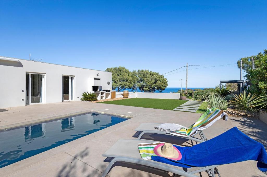 a villa with a swimming pool and two lounge chairs at Blava in Begur