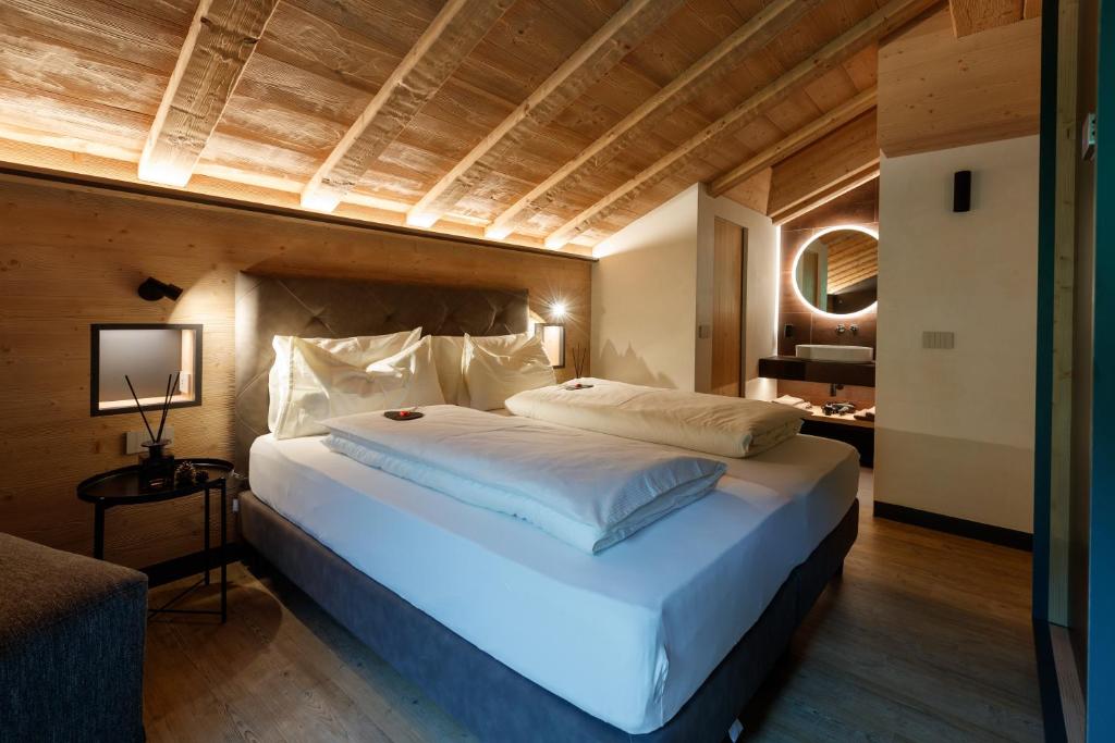 a bedroom with a large white bed with a wooden ceiling at Chalet Ice Villa Genf Spa - Relax in Livigno
