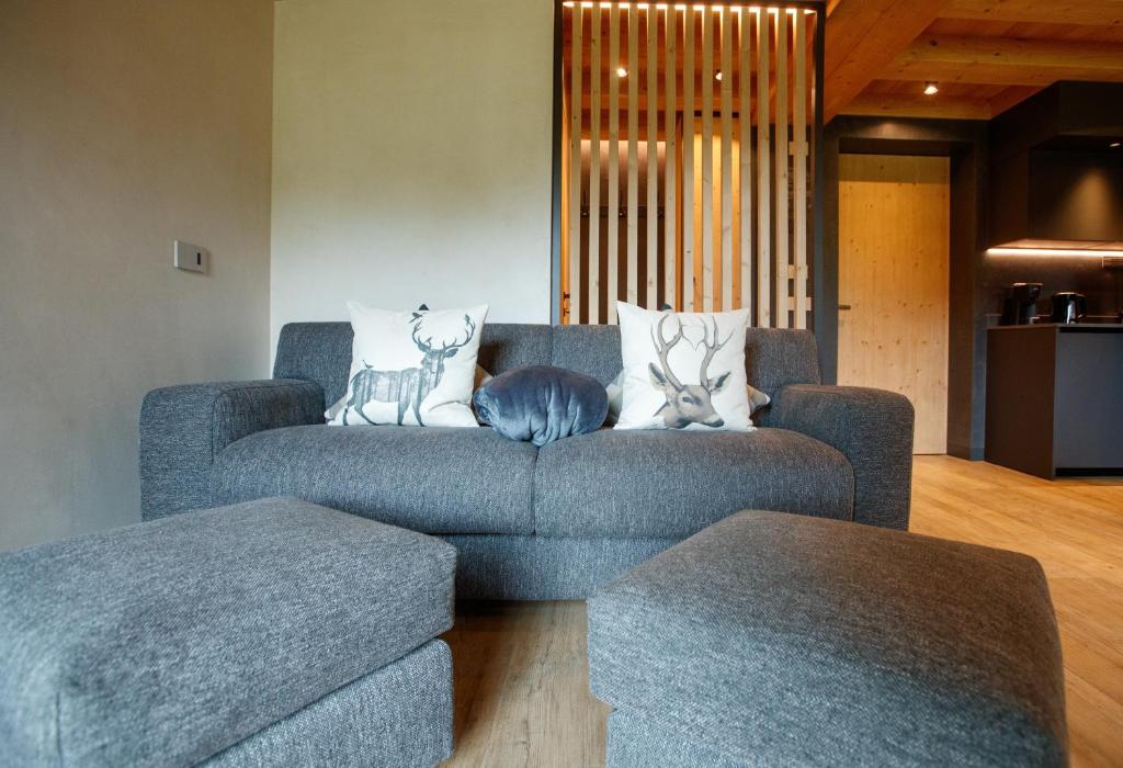 a living room with a blue couch with two deer pillows at Sun Villa Genf Spa - Relax in Livigno