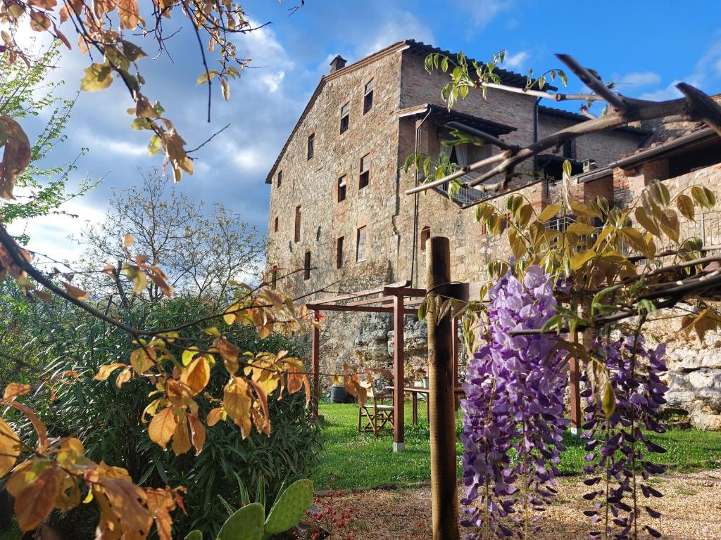 an old building with purple flowers in front of it at Casa vacanze Santa Giulia in Monteriggioni