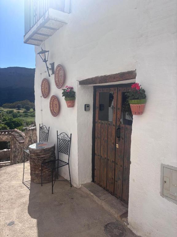 a white building with a door and a table and chairs at Casa Buena Vista in Ugíjar